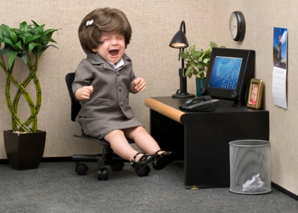 Baby dressed in professional office attire crying at her desk
